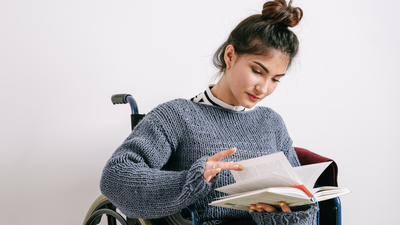 Woman sitting in wheelchair reading a book. Used to display person with disability in an article about laws designed to protect people facing health challenges.
