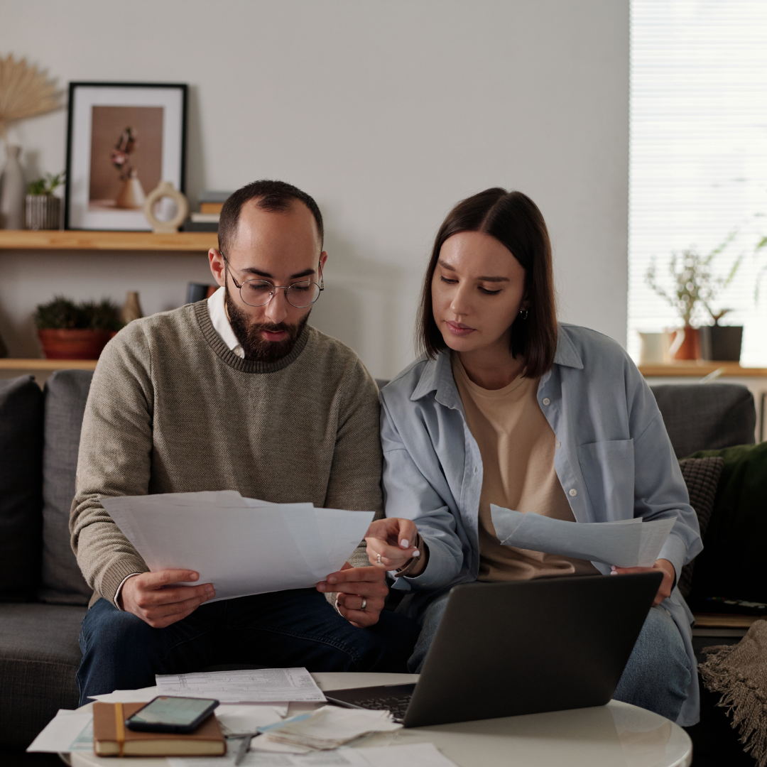 Man and woman sitting on couch, looking over bills