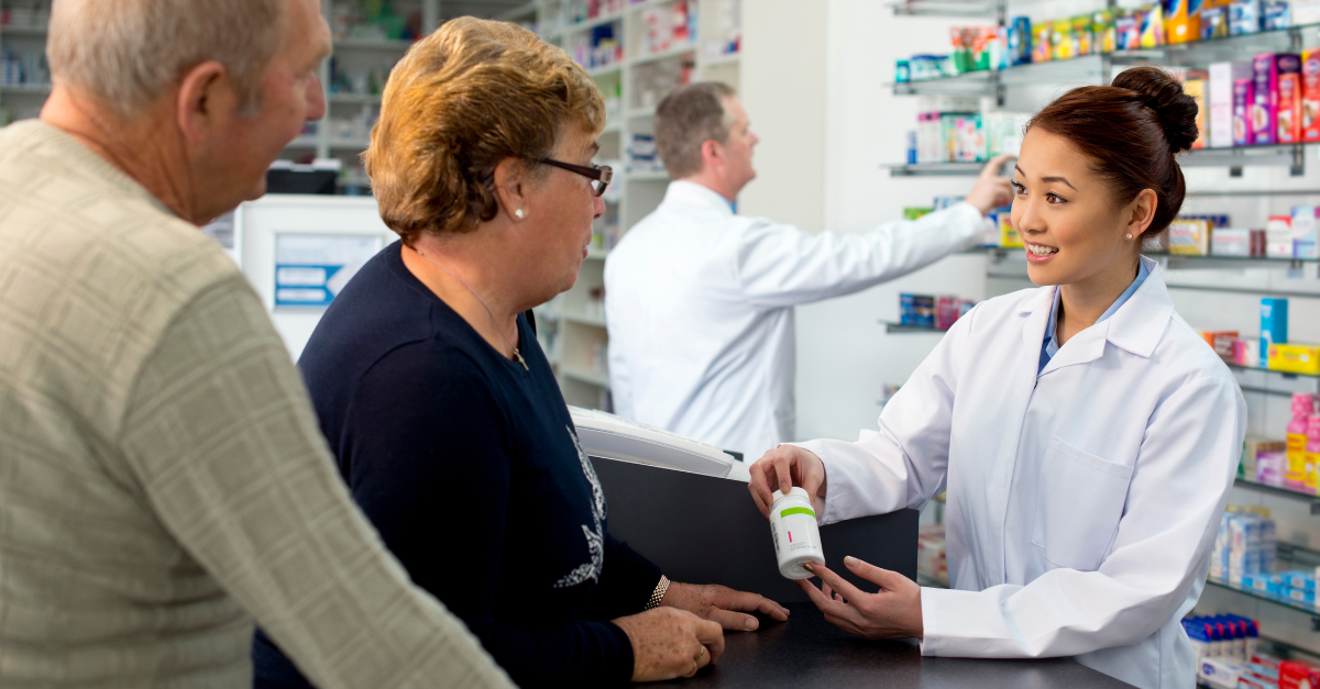 Pharmacist shows man and woman their prescription medication