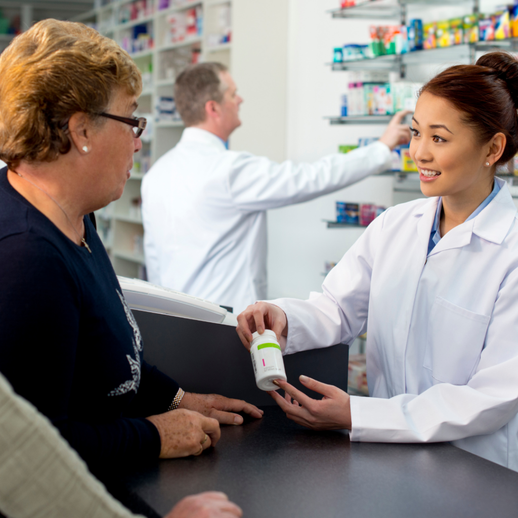 Pharmacist shows man and woman their prescription medication
