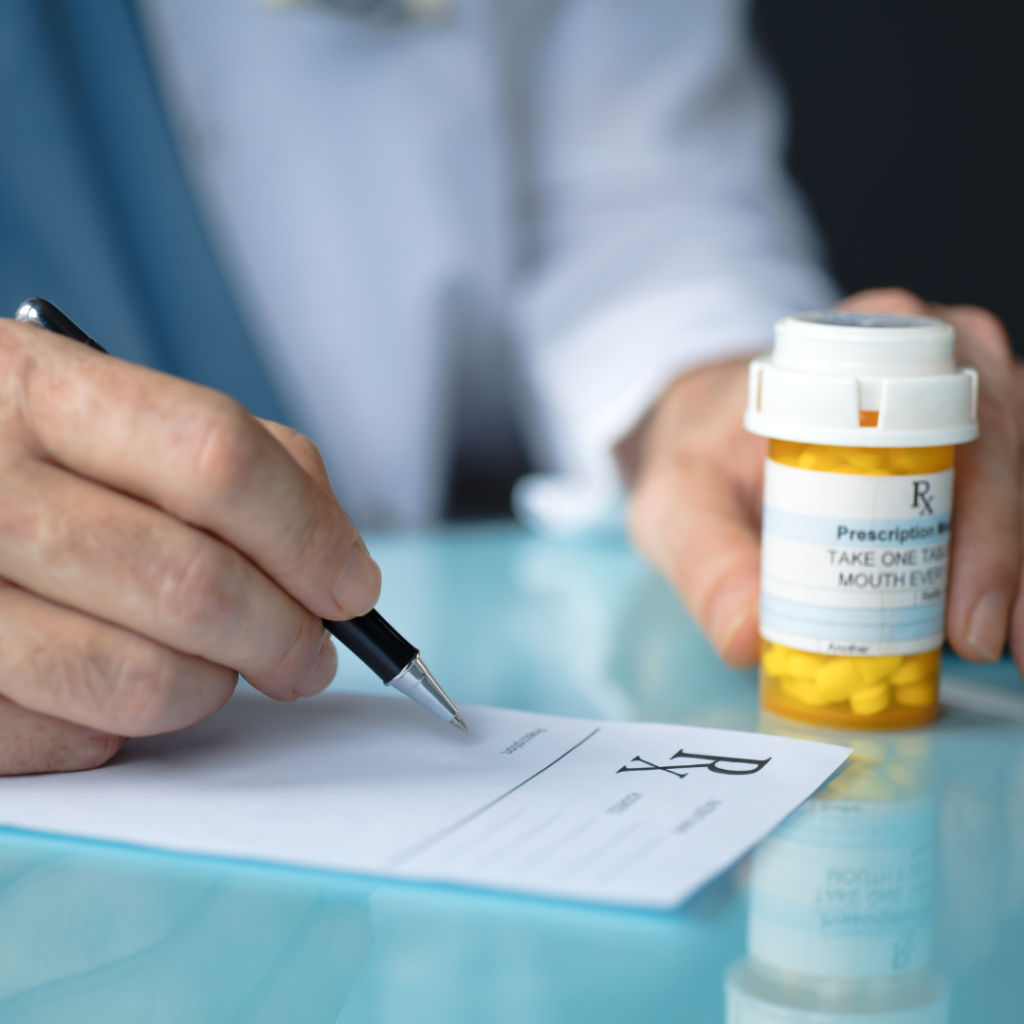 Person signing prescription and holding medication in hand
